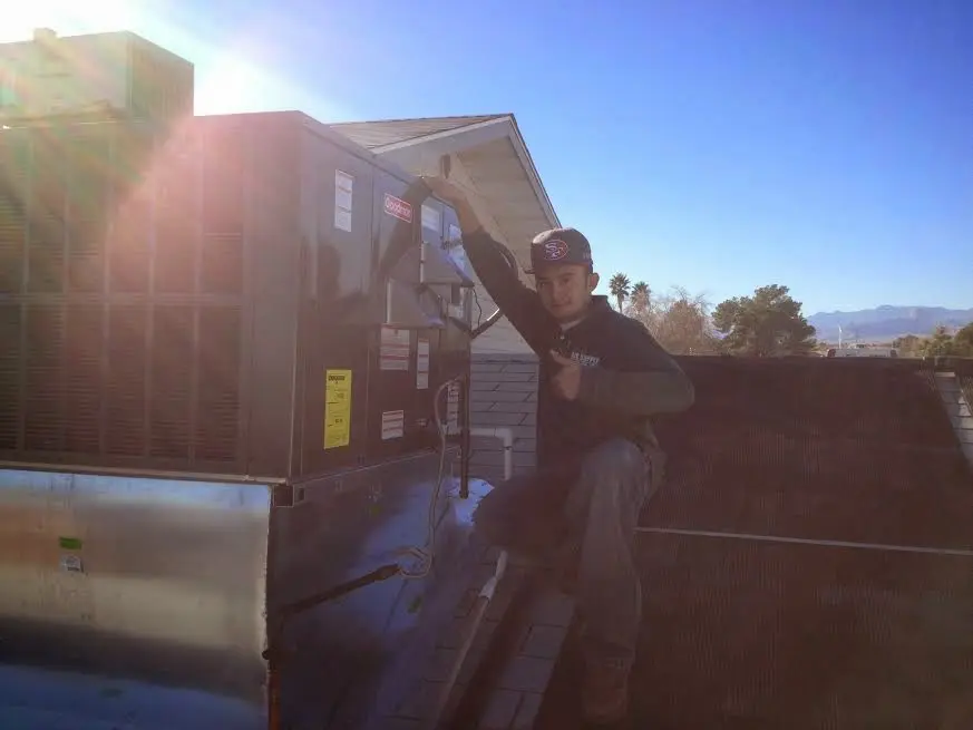 HVAC technician performing Air Duct Repair on a rooftop unit in Newcastle