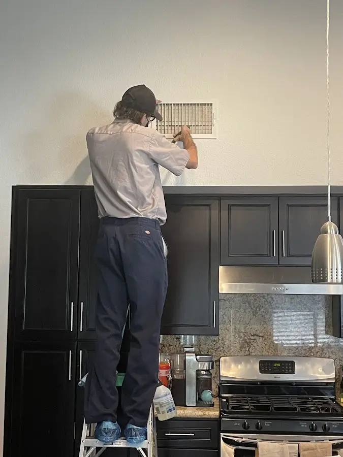 Technician inspecting an air vent during HVAC service in Newcastle